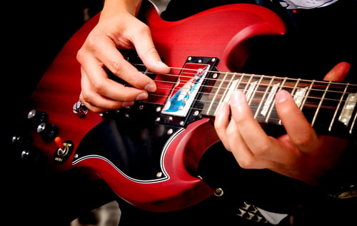 electric guitar close up with fingers playing it